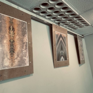 Pod sufitem zawieszone są zawieszone w antyramach z drewnianym tłem trzy zdjęcia. Przedstawiają w dużym przybliżeniu elementy natury.