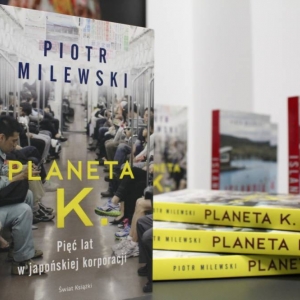 Zbliżenie na stół, na którym ustawione są jedna za drugą książki z tytułem "Planeta K. Pięć lat w japońskiej korporacji". W tle widać rozmazaną książkę pt. "Islandia".