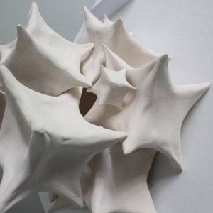 Fragment elementów ceramicznej rzeźby. Konstrukcję tworzą kostki, których rogi są lekko spłaszczone. Kostki mają różne rozmiary i nałożone są jedna na drugą.