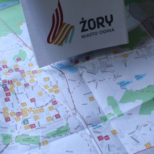 Zbliżenie na stolik z rozłożoną mapą Żor wraz kartą z logo Żor i kolorami.