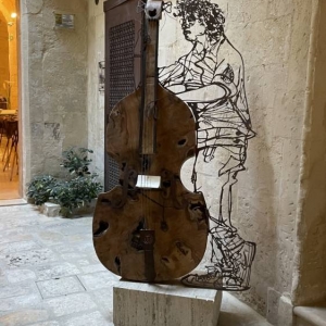 Zdjęcie metalowej rzeźby przedstawiającej mężczyznę grającego na wiolonczelli.